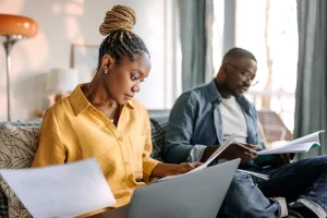 Couple reviewing documents together at home with a laptop.