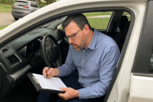 A professional appraiser inspecting a vehicle to make a repair estimate