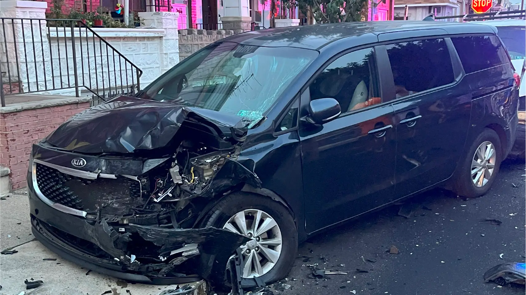 Front view of a heavily damaged black Kia minivan involved in a serious accident, illustrating the concept of total loss vehicle under Texas law.