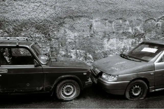 Two old cars involved in a front-to-front collision, representing vehicle accidents and car damage assessments.