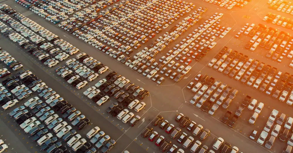 Aerial view of a large car export lot filled with rows of cars ready for shipment, illustrating China’s record 38% increase in car exports in April 2024.