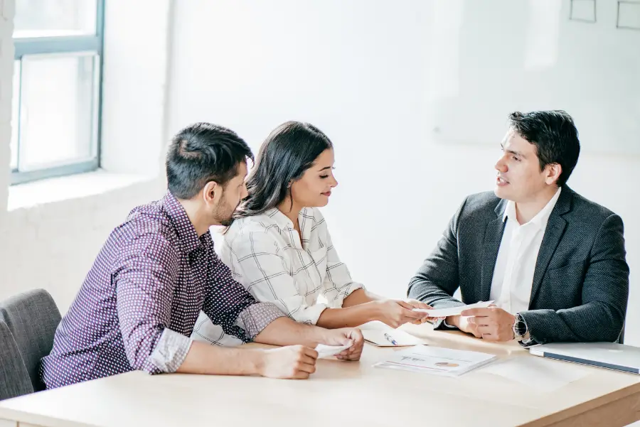 A couple consulting with a professional advisor at an office, discussing insurance and financial solutions for the sharing economy.