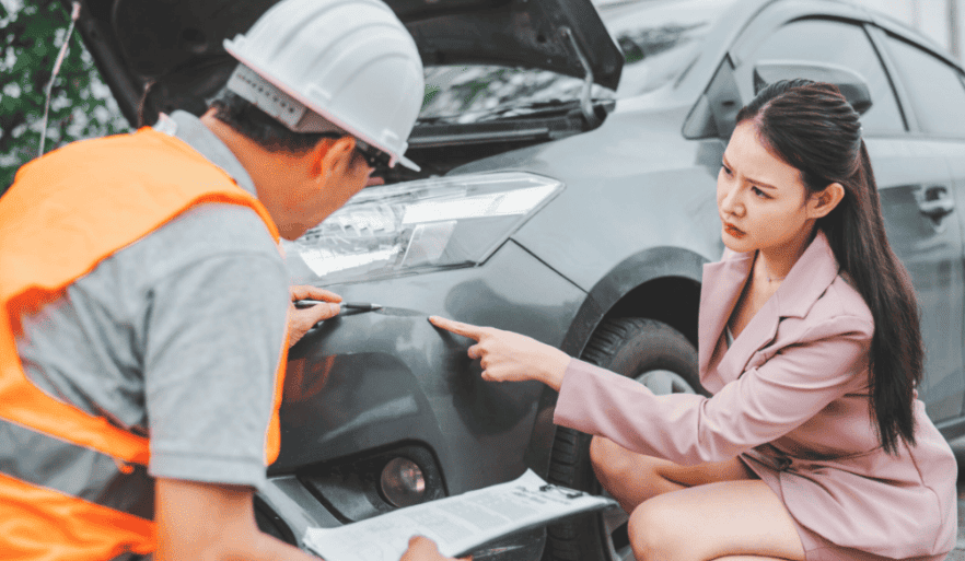 Car owner pointing at vehicle damage while insurance adjuster takes notes during inspection for comparable valuation claim