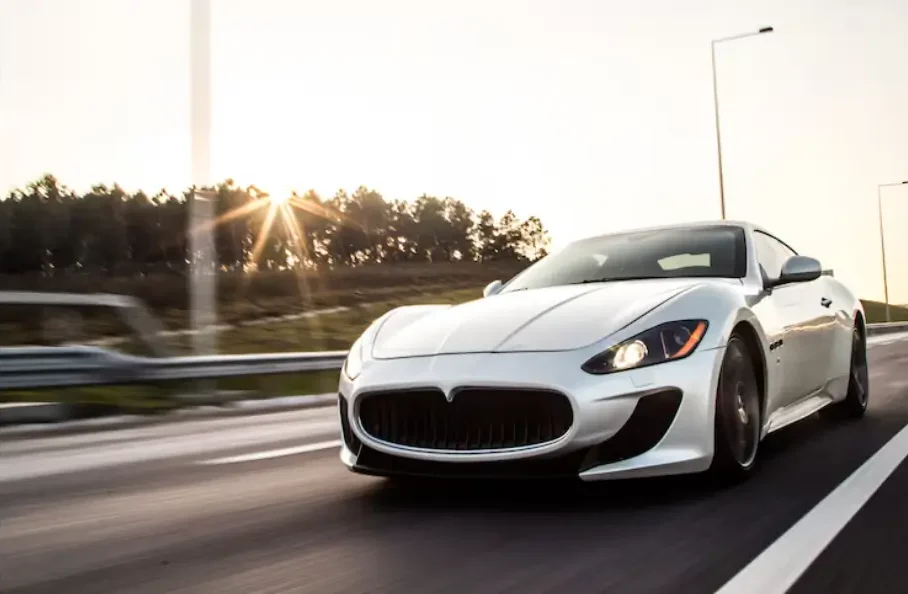 White luxury sports car speeding on a highway at sunrise, highlighting performance, elegance, and modern automotive engineering.