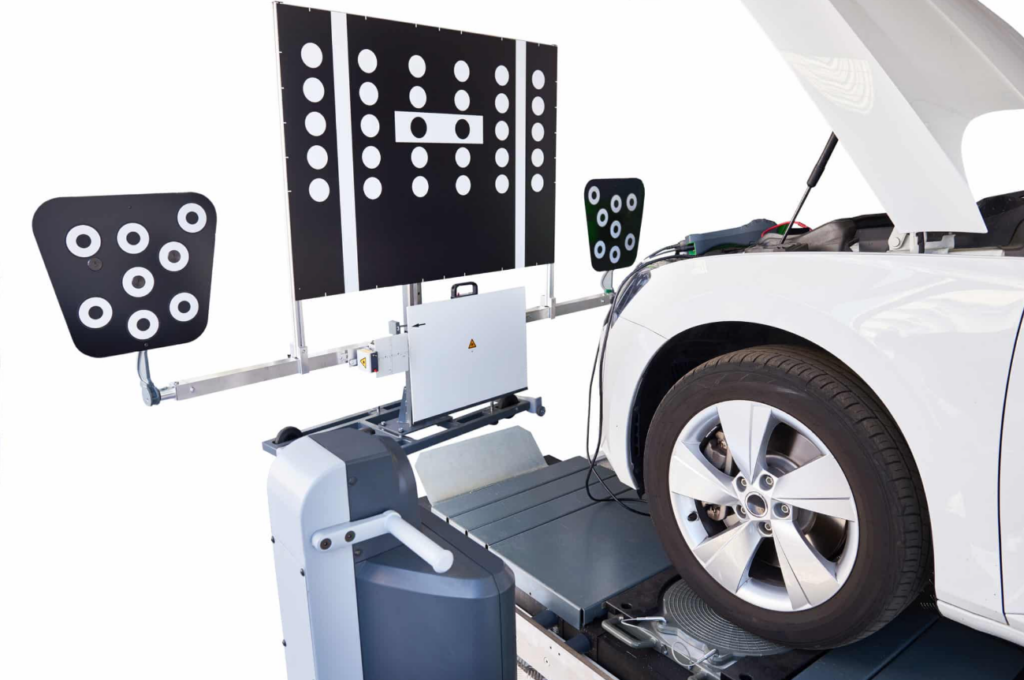ADAS calibration equipment with target panels positioned in front of a white car during static sensor calibration in a repair shop
