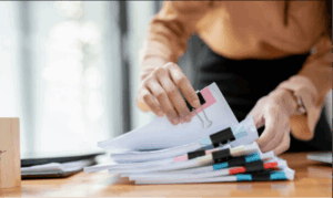 Person sorting stacks of loan and tax paperwork needed to claim the car loan interest deduction