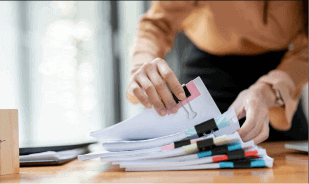 Person sorting stacks of loan and tax paperwork needed to claim the car loan interest deduction