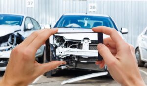 man photographing his vehicle with damages accident insurance with smartphone