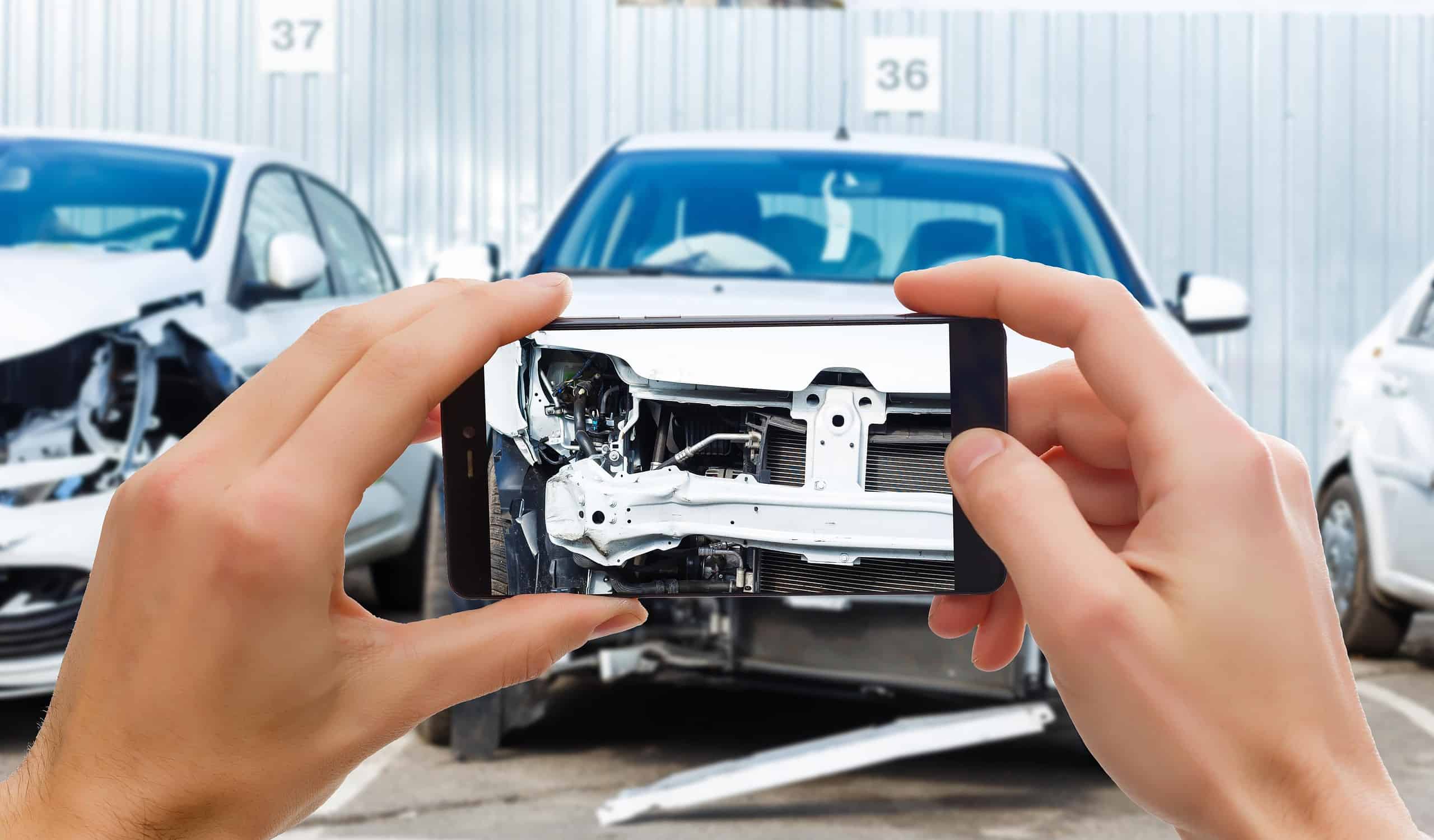 man photographing his vehicle with damages accident insurance with smartphone