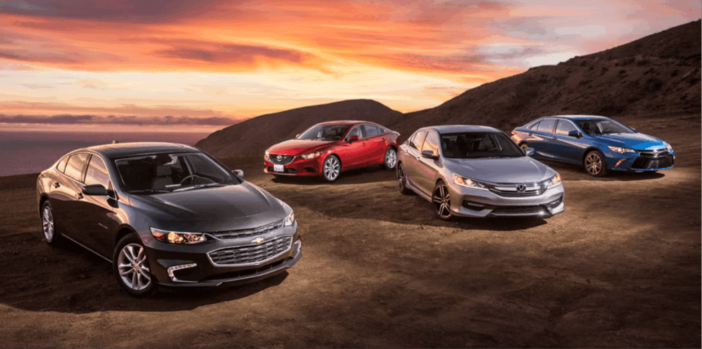 Four mid-size sedans parked together at sunset showing the vehicle segment losing the most wholesale value in 2026