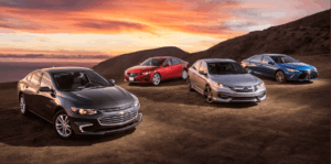 Four mid-size sedans parked together at sunset showing the vehicle segment losing the most wholesale value in 2026