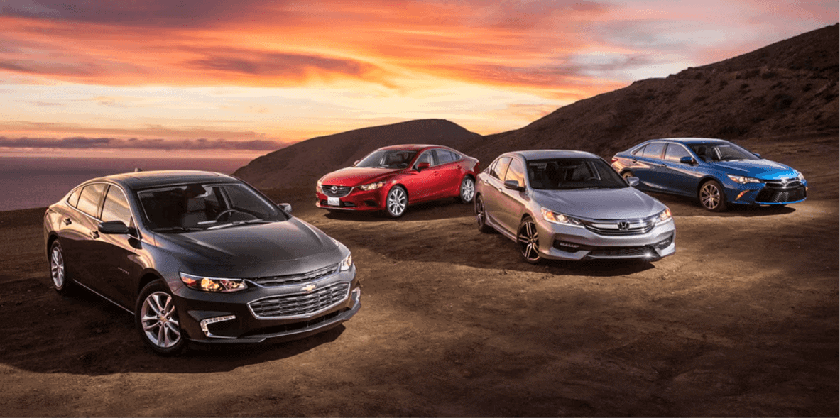 Four mid-size sedans parked together at sunset showing the vehicle segment losing the most wholesale value in 2026