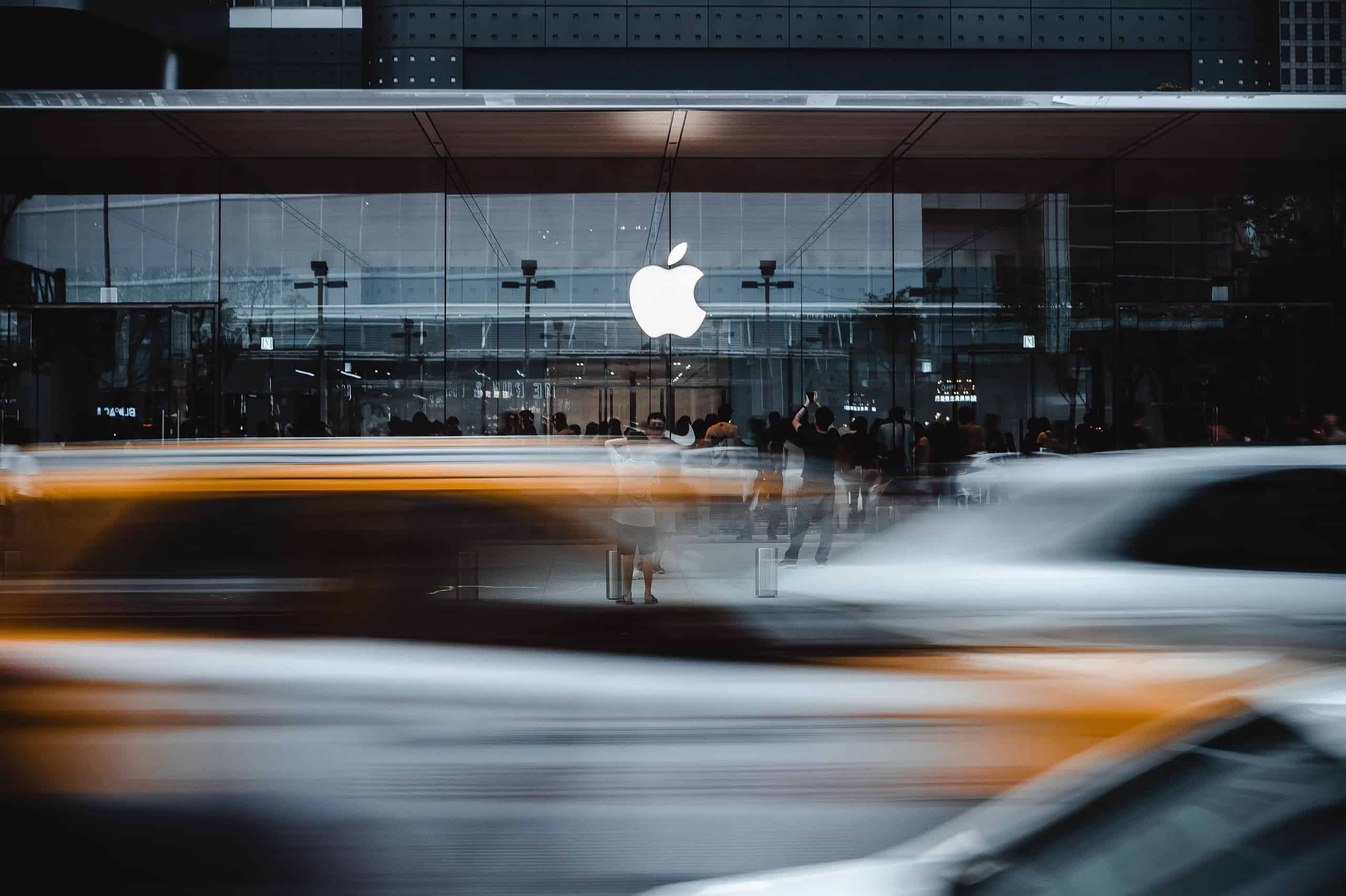 people and traffic in front of an apple building