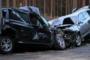 Two heavily damaged cars after a head-on collision on a forest road
