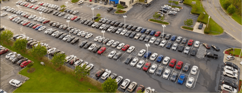 Aerial view of a car dealership parking lot filled with rows of new vehicles illustrating vehicle affordability challenges