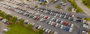 Aerial view of a car dealership parking lot filled with rows of new vehicles illustrating vehicle affordability challenges